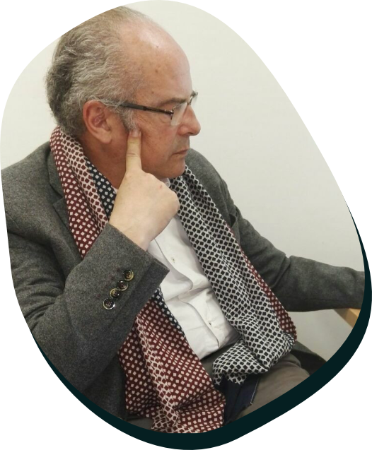 Jesus Ambel, fundador de ambel psicologos sentado mirando unas notas, hombre de pelo grisaceo con gafas y una chaqueta gris